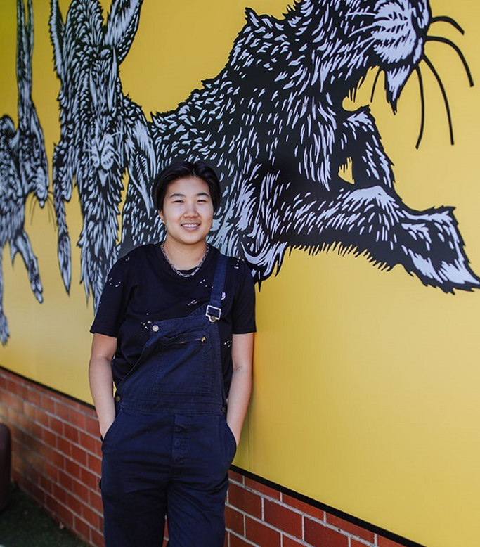 artist standing in front of artwork in fish lane